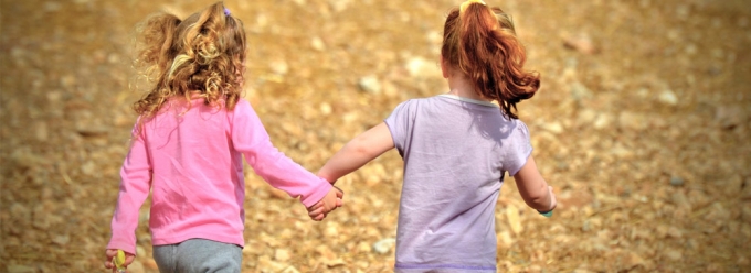 Two little girls holding hand and running